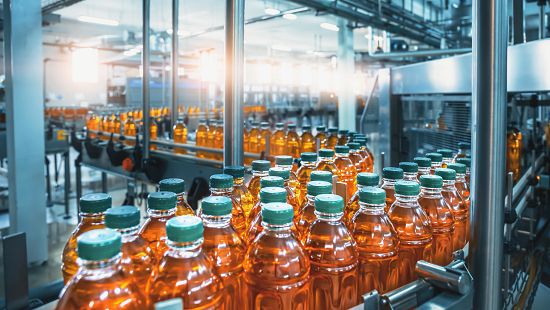 Production line of apple juice being bottled in processing plant.
